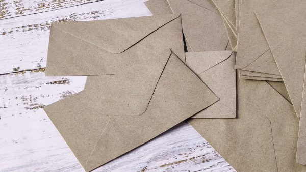 Espapel sobre de papel (1) Sobres de papel kraft apoyados sobre un escritorio de madera