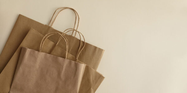 Espapel bolsas de asa (5) Bolsas de papel kraft amontonadas sobe un fondo crema oscuro